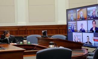 man seated in front of large screen tv in court