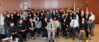 group of students with hosts in courtroom posed for photo