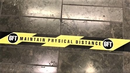 socially distance guidance on yellow and black floor tape