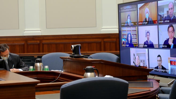 man seated in front of large screen tv in court