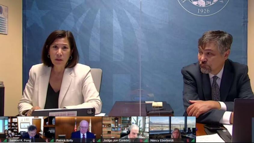 chief justice and martin hoshino seated in room presenting on teleconference