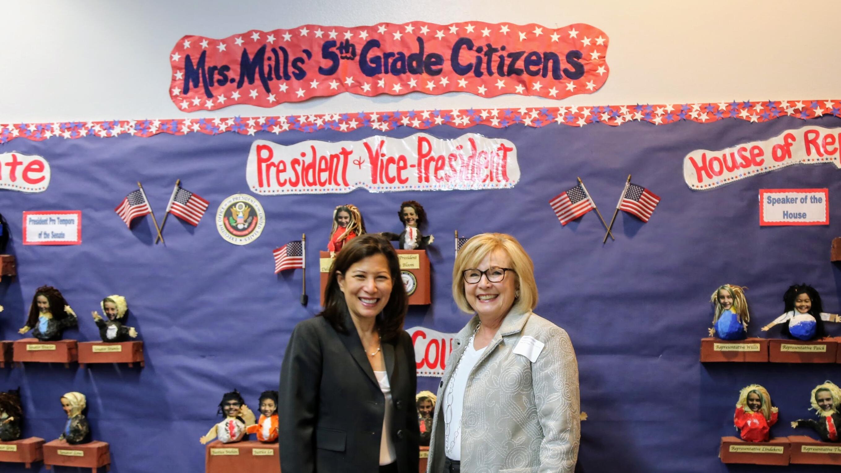 Chief justice and justice mcconnell standing in front of mural inside a classroom