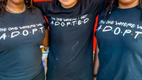 youth standing with arms around two women wearing adopt tshirts