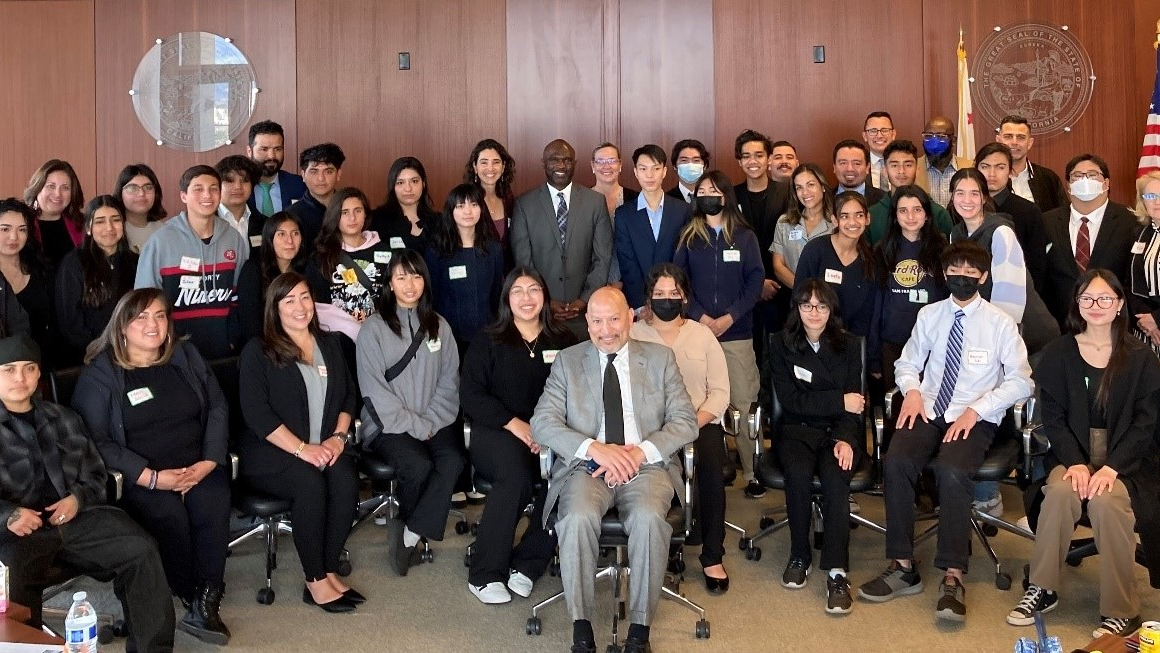 group of students with hosts in courtroom posed for photo