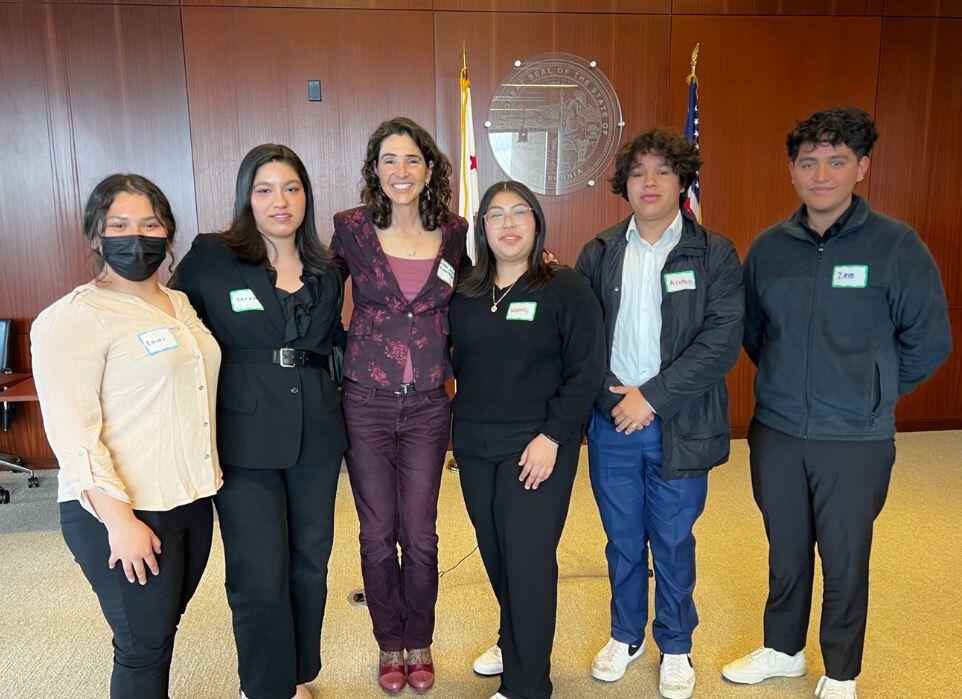 judge standing in courtroom surrounded by young adults