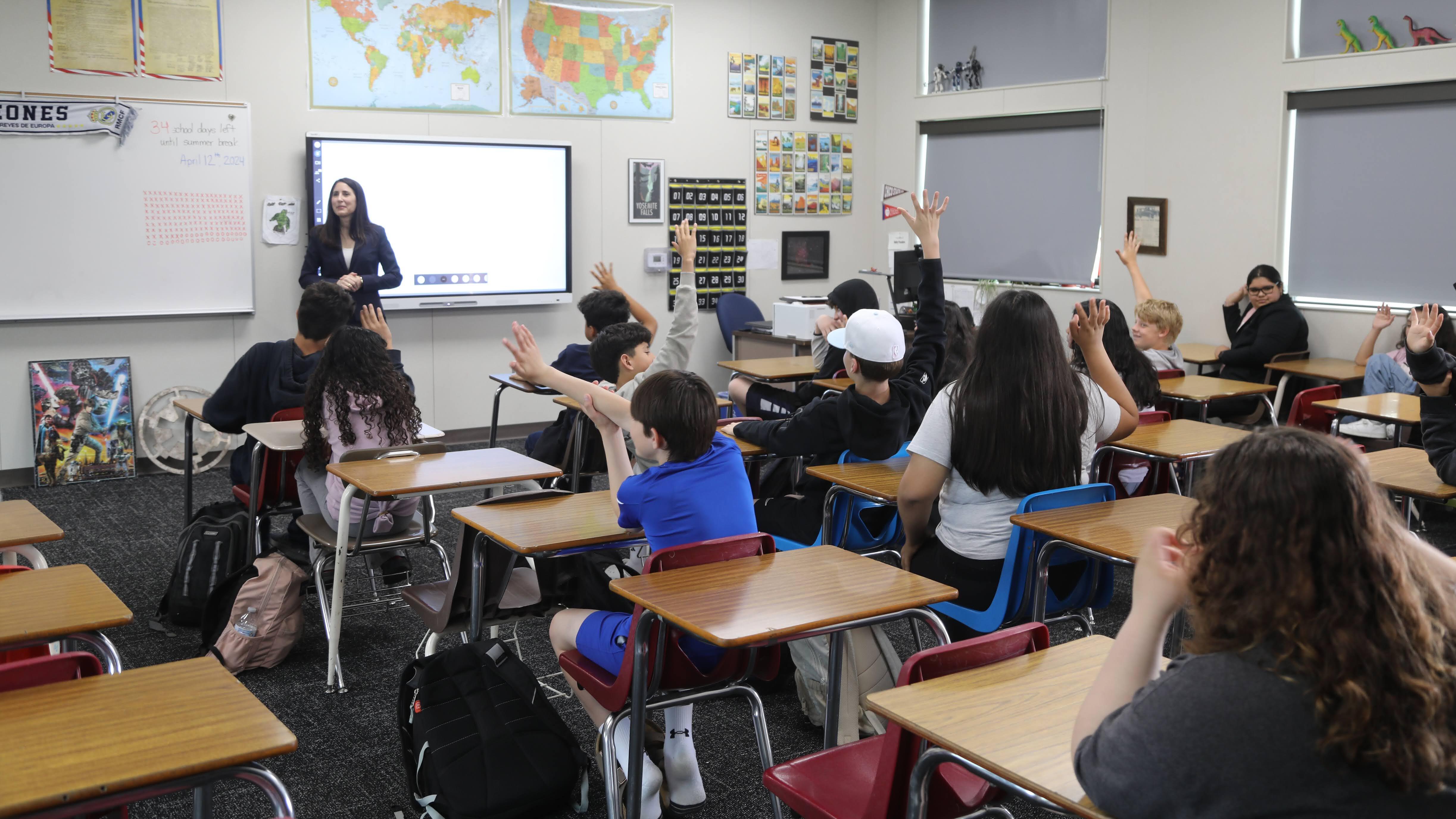 large classroom of students seated with woman speaking