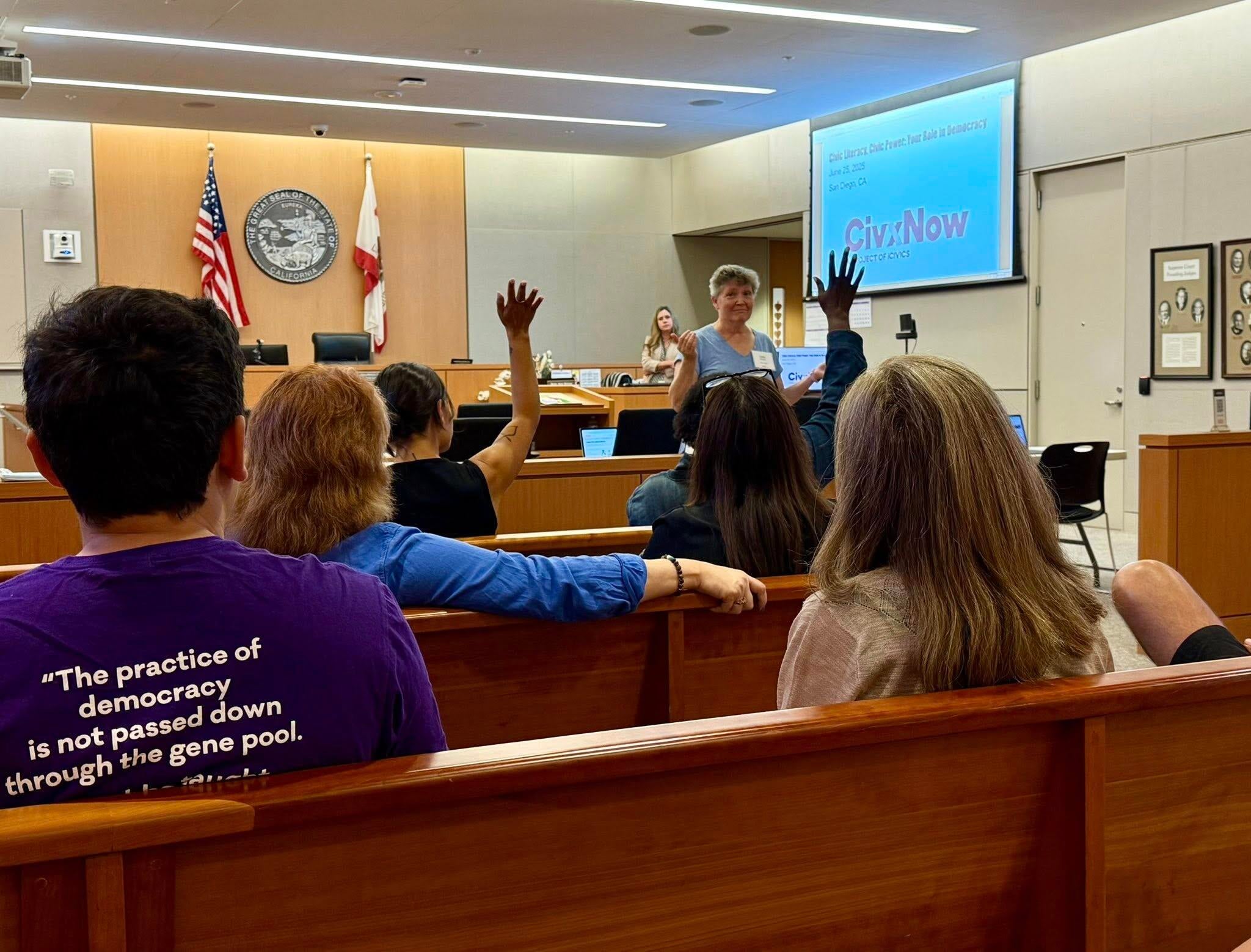 teachers seated in courtroom with hands raised