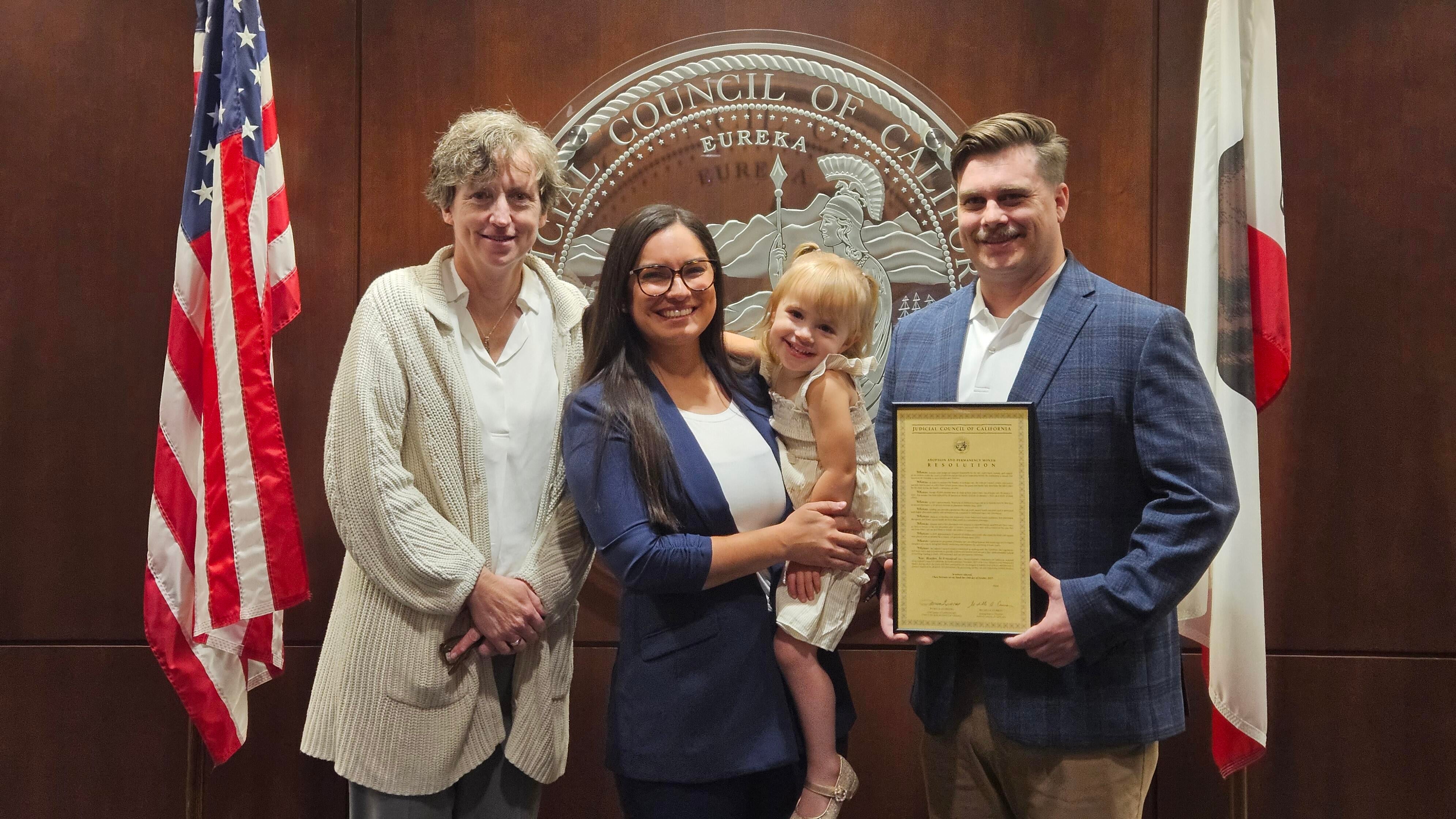 From Left to Right: Judicial Council Administrative Director Shelley Curran, Claudia, "Cece", Michael. All standing between the American flag and the California flag.