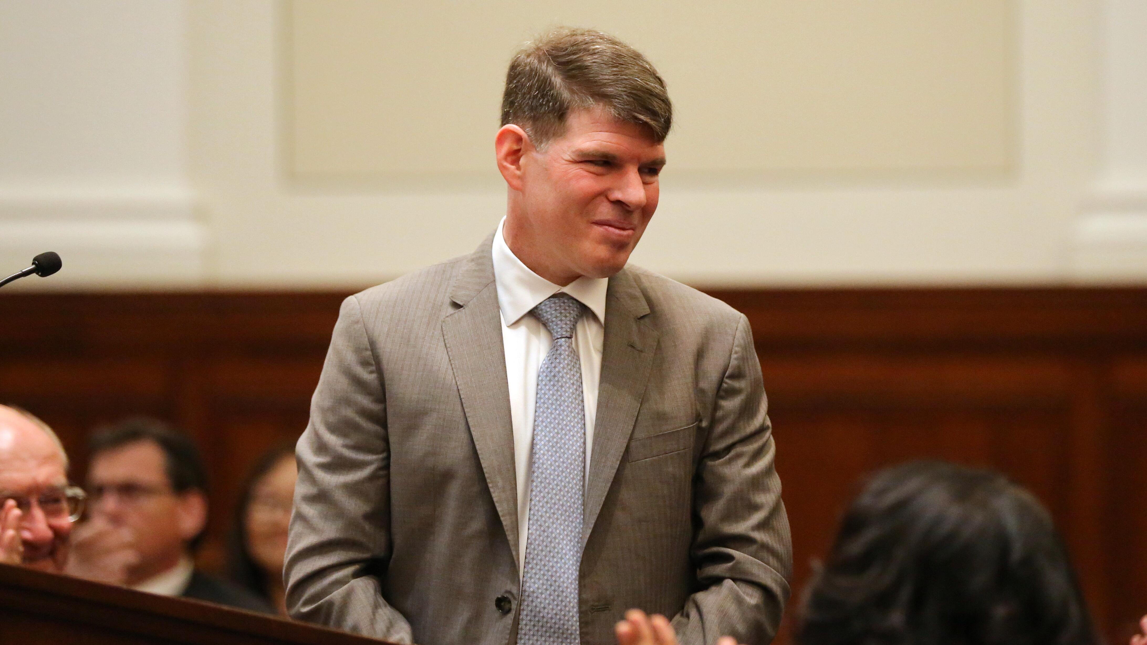 Associate Justice Matthew Scherb in formal attire standing at podium during his confirmation hearing.