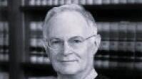 Justice Daniel J Kremer in judicial attire in front of bookshelf.