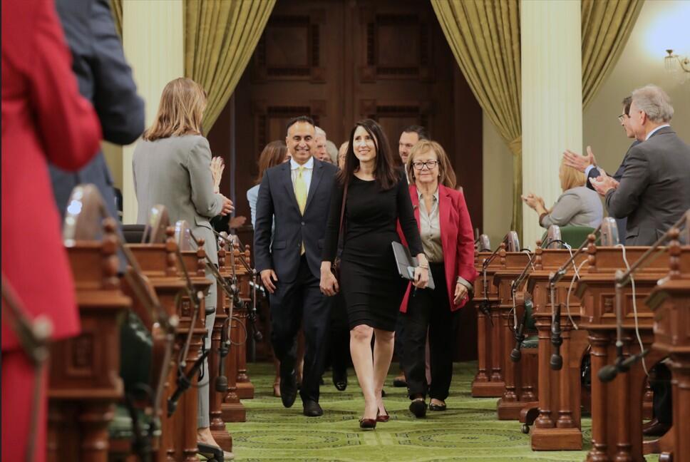 People walking into a large room being welcomed by attendees