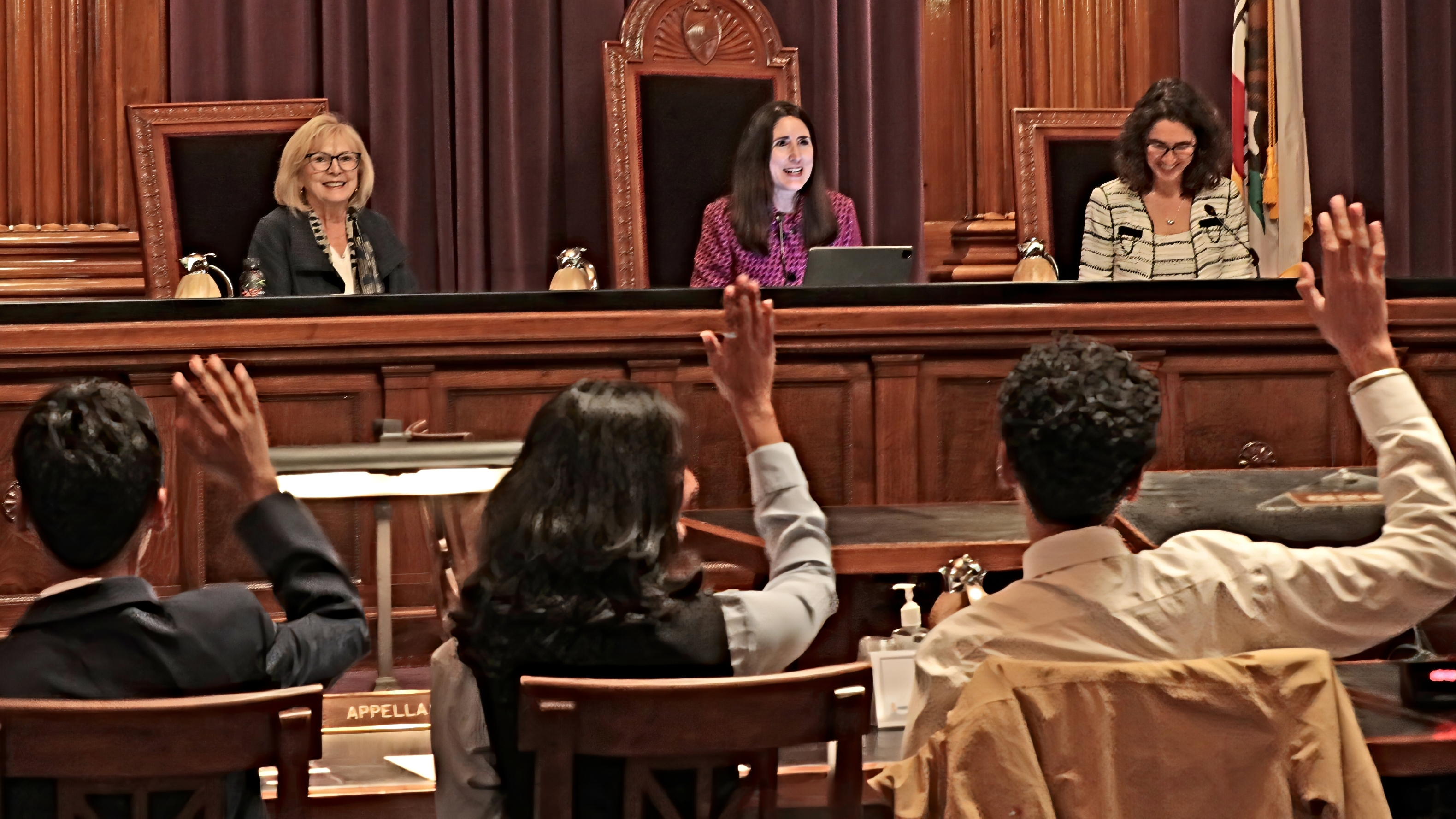 Judicial officers sit in chairs facing a row of students raising hands