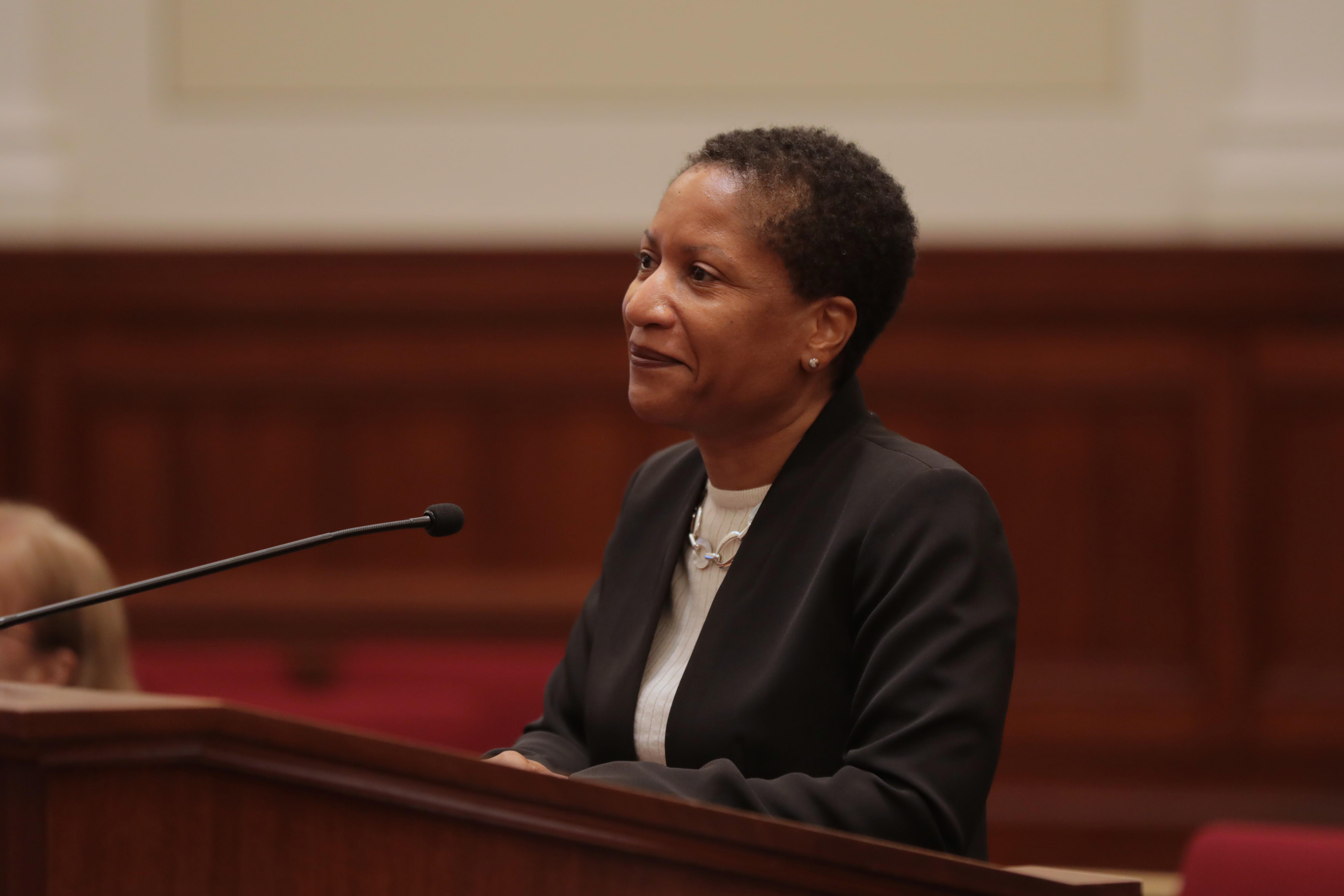 Presiding Justice Rashida Adams stands in front of a wooden podium. 