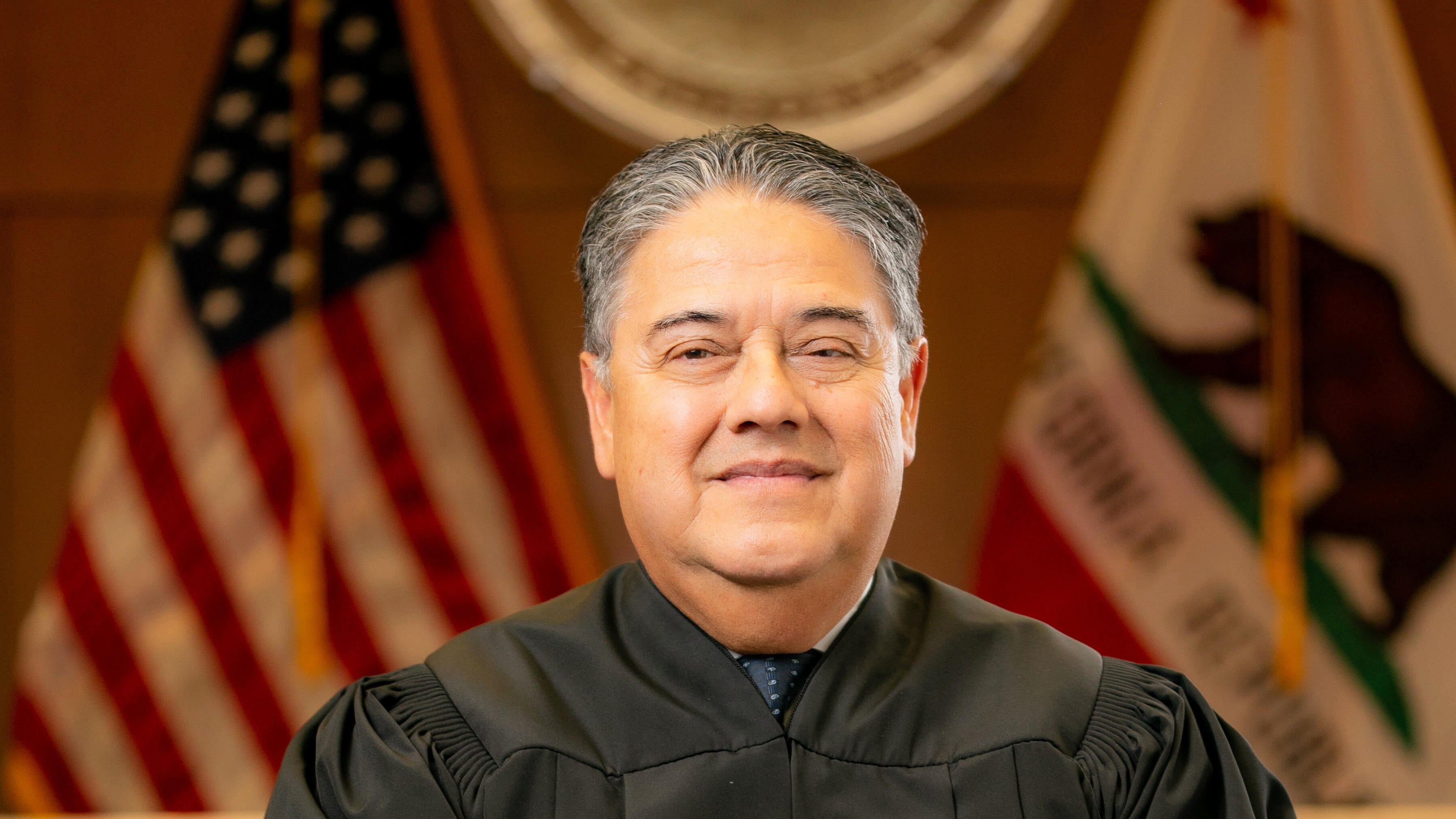Justice Maurice Sanchez stands in judicial attire.