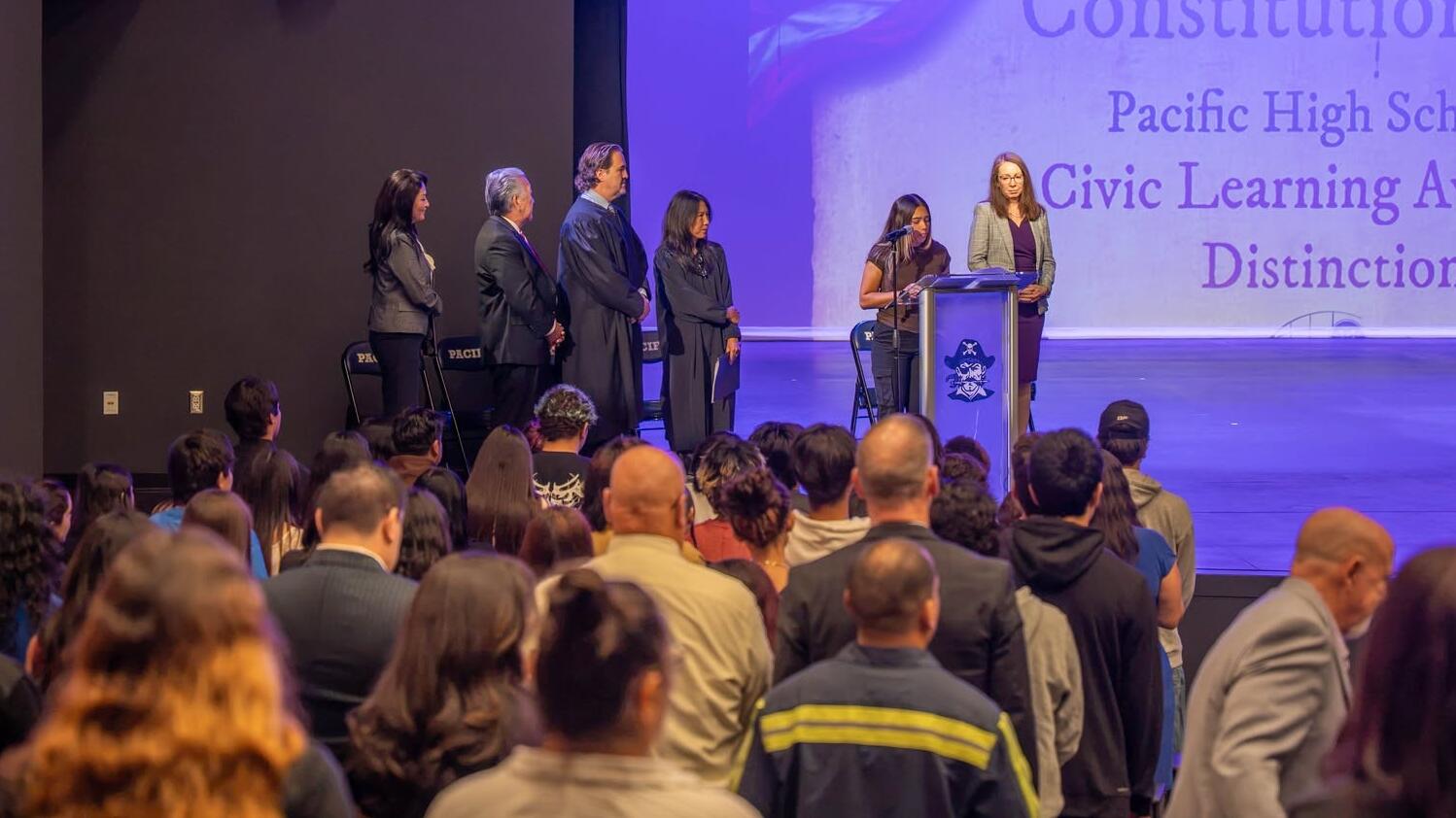 Justice presents plaque in an auditorium.