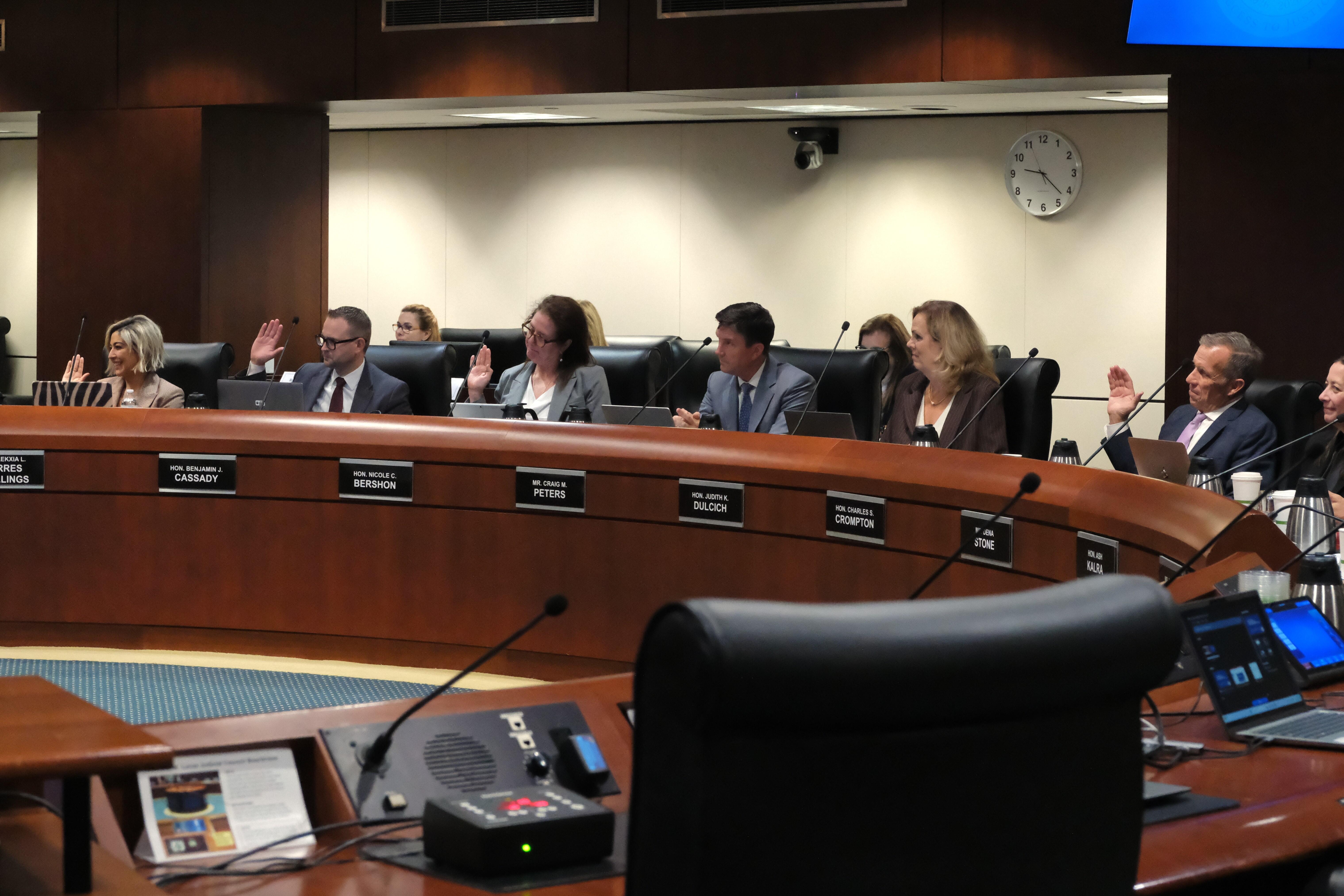 Alekxia L. Torres Stallings, Commissioner Benjamin J. Cassady, and Judge Nicole C. Bershon sit in a row in front of the dark wooden roundtable. Their right hands are raised for their swearing in.
