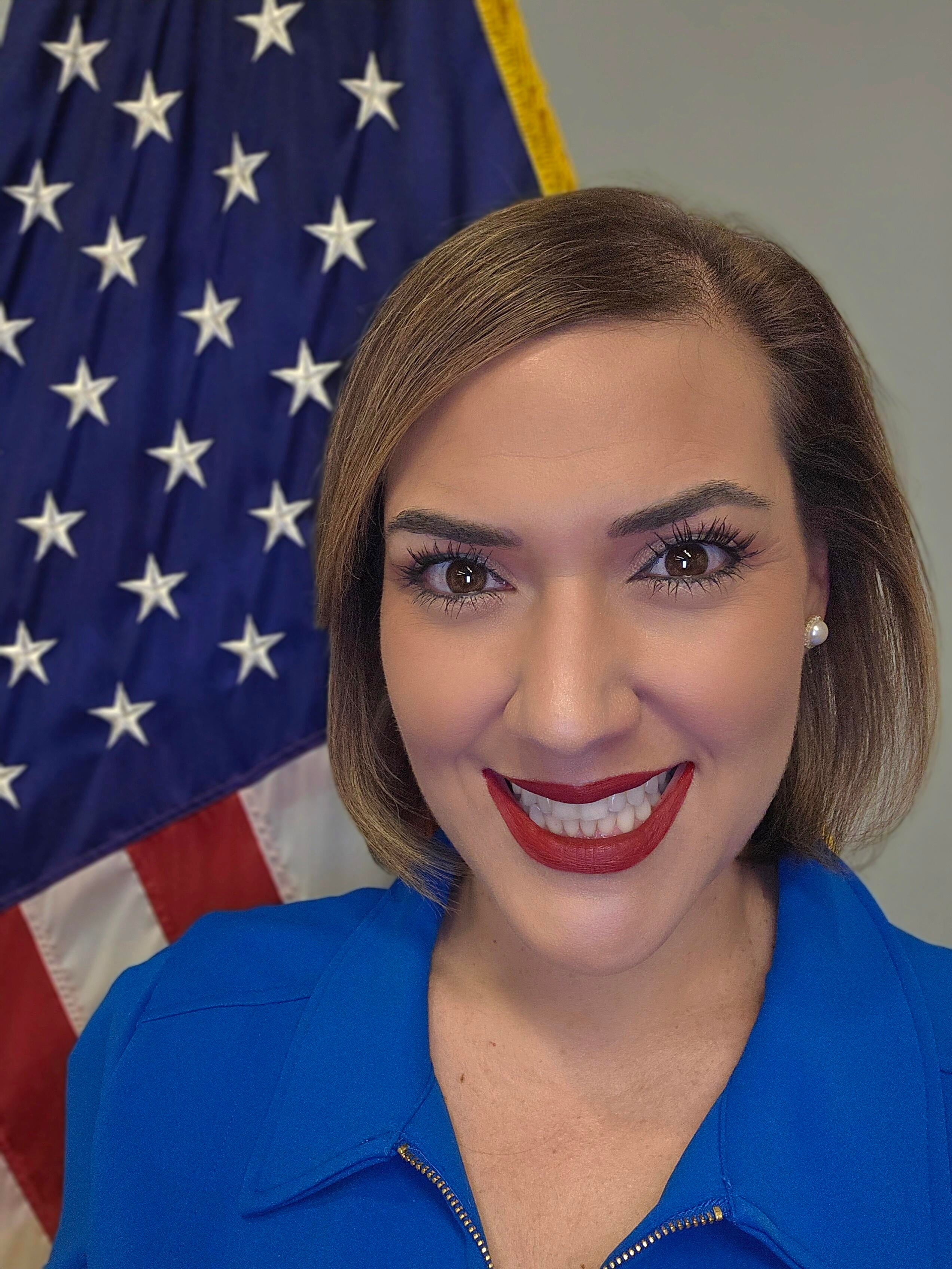 Janet Gamboa stands in front of the United States flag.