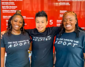 youth standing with arms around two women wearing adopt tshirts