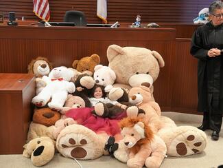inside courtroom pile of stuffed bear surrounding a child