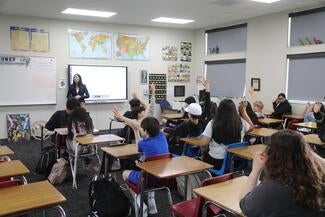large classroom of students seated with woman speaking