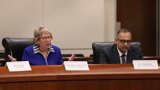 Two presenters sit in the Judicial Council boardroom