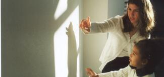 Woman with a child making shadow figures - Photo by Jason Doiy