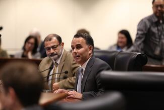 Two presenters sit in the Judicial Council boardroom