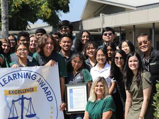 group of students with chief justice outside with Civic Learning Award banner