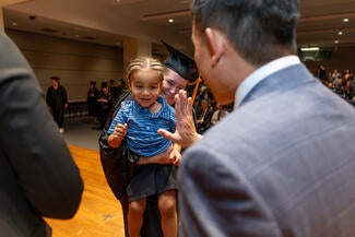 Person holding a young person giving a high five to another person