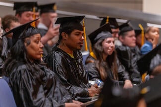 people dressed in graduation caps and gowns sitting in an auditorium