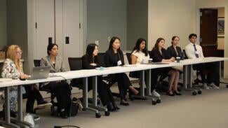 Students at long table listening to presentation