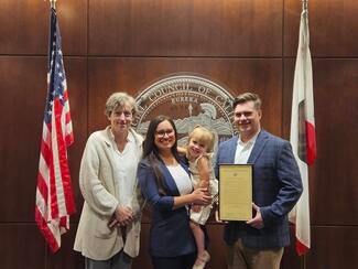 From Left to Right: Judicial Council Administrative Director Shelley Curran, Claudia, "Cece", Michael. All standing between the American flag and the California flag.