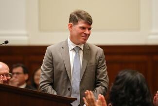 Associate Justice Matthew Scherb in formal attire standing at podium during his confirmation hearing.