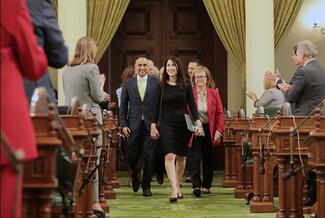 People walking into a large room being welcomed by attendees