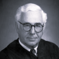 Man with glasses in judicial attire.