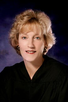 Woman in judicial attire faces camera.