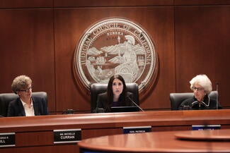 Three people sitting at a boardroom table