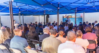 Crowd of people sitting under a tent listening to a speaker