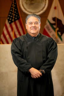 Justice Maurice Sanchez stands in judicial attire.