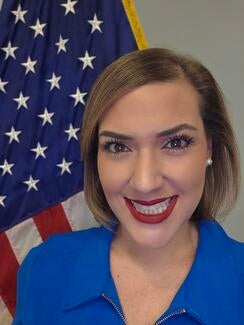 Janet Gamboa stands in front of the United States flag.